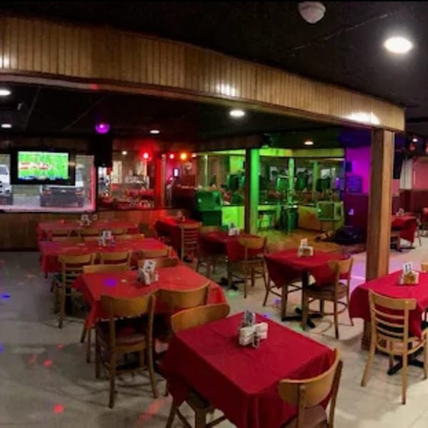 Interior of Havana Club Restaurant & Bar with red tablecloths, wooden chairs, and colorful lighting.