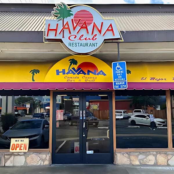 Exterior of Havana Club Restaurant & Bar with a vibrant yellow and purple awning and an "OPEN" sign.