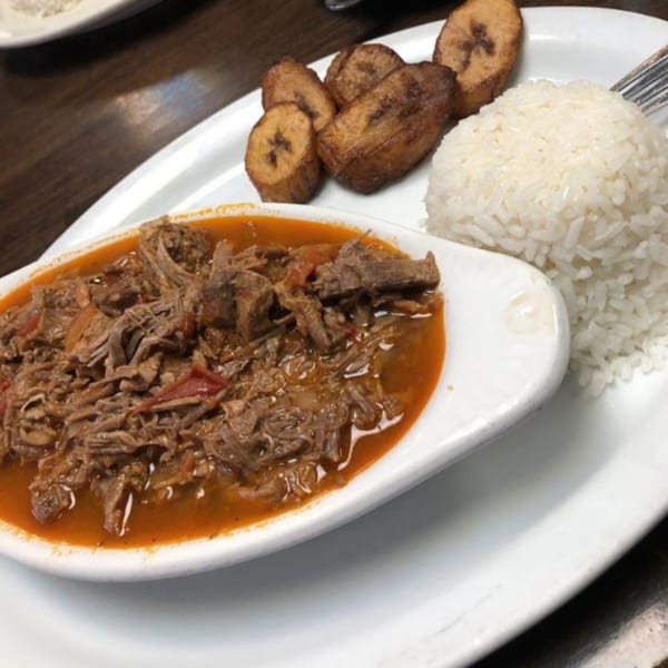 Ropa Vieja with white rice and fried plantains on a white plate at Havana Club Restaurant.