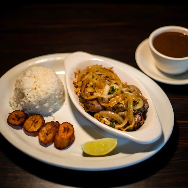 Cuban dish with rice, fried plantains, lime, and meat topped with onions and sauce, with coffee.