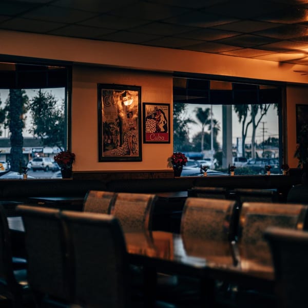 Interior of Havana Club Restaurant & Bar with Cuban posters, tables, and large windows.